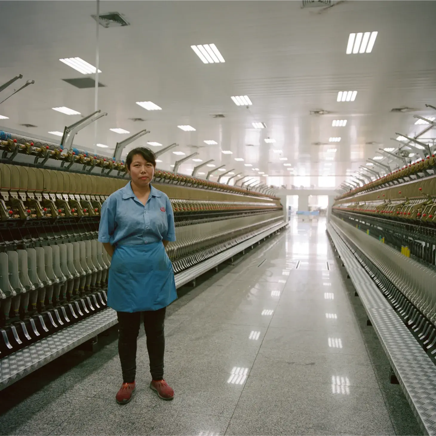woman standing in a row of industrial sowing machines
