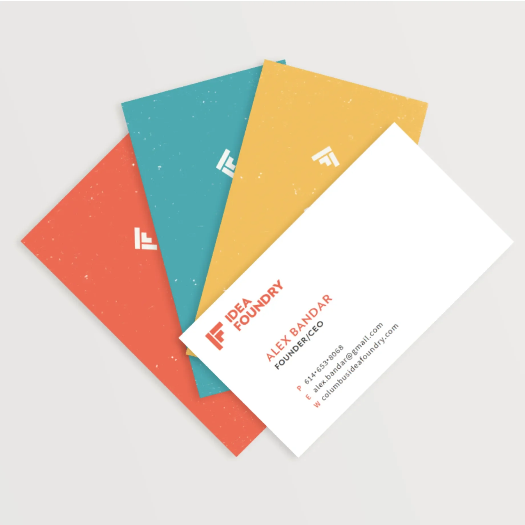 A fan of four Idea Foundry business cards, each with a branded color on the back