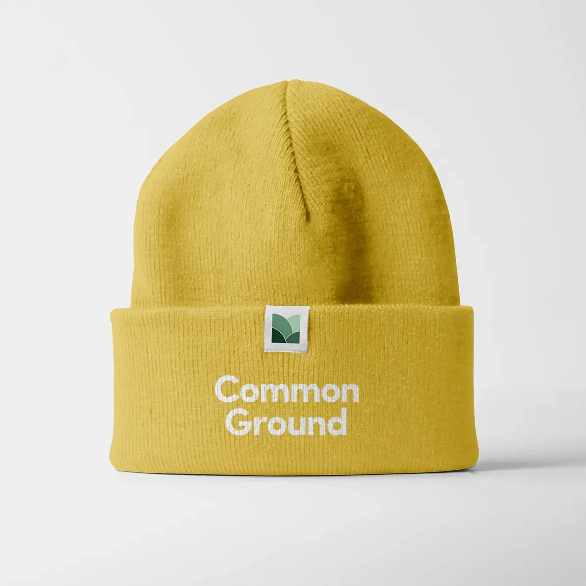 yellow maymont branded beanie hat with the words common ground on it