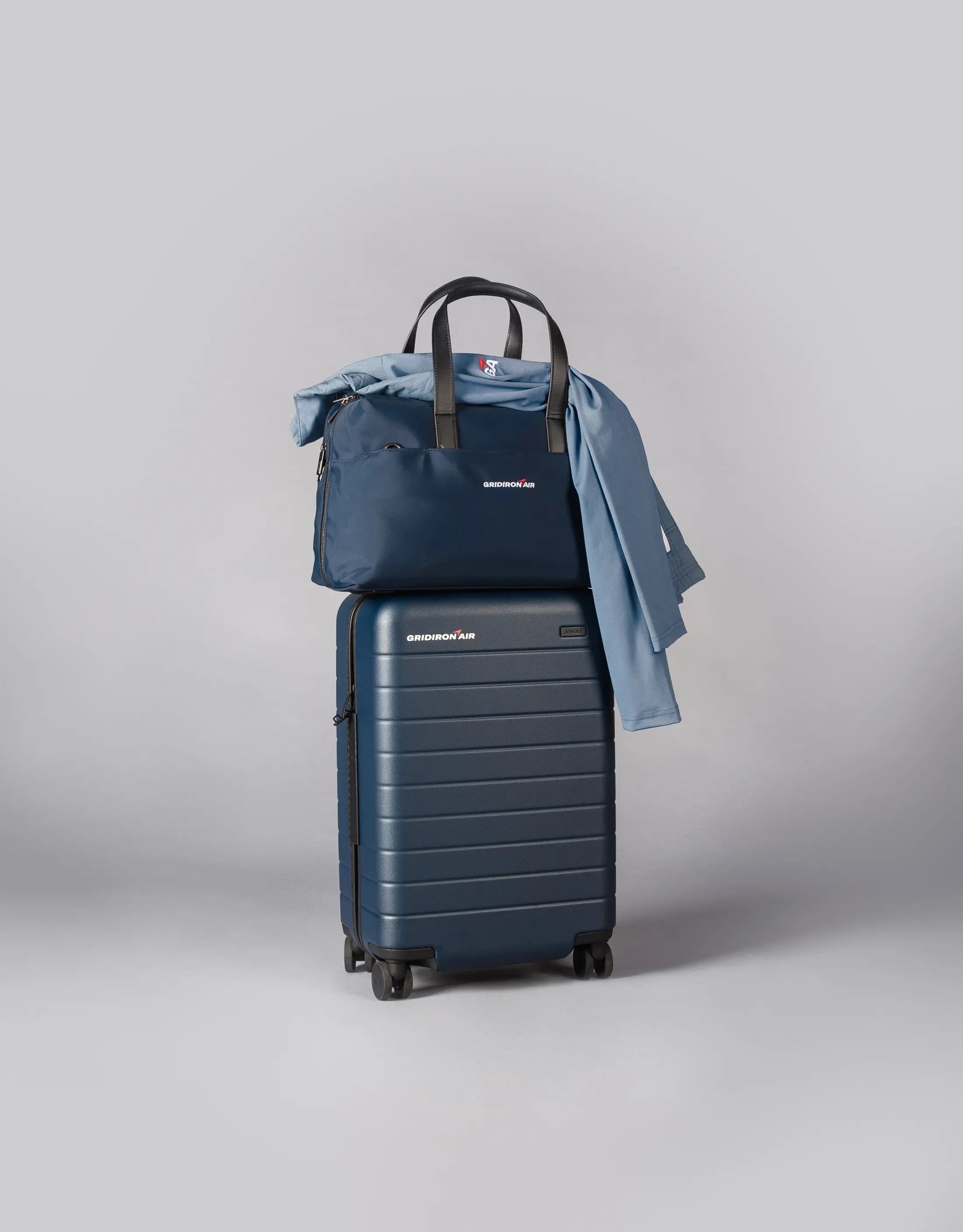 custom luggage stacked with a shirt draped over top, all branded with gridiron air