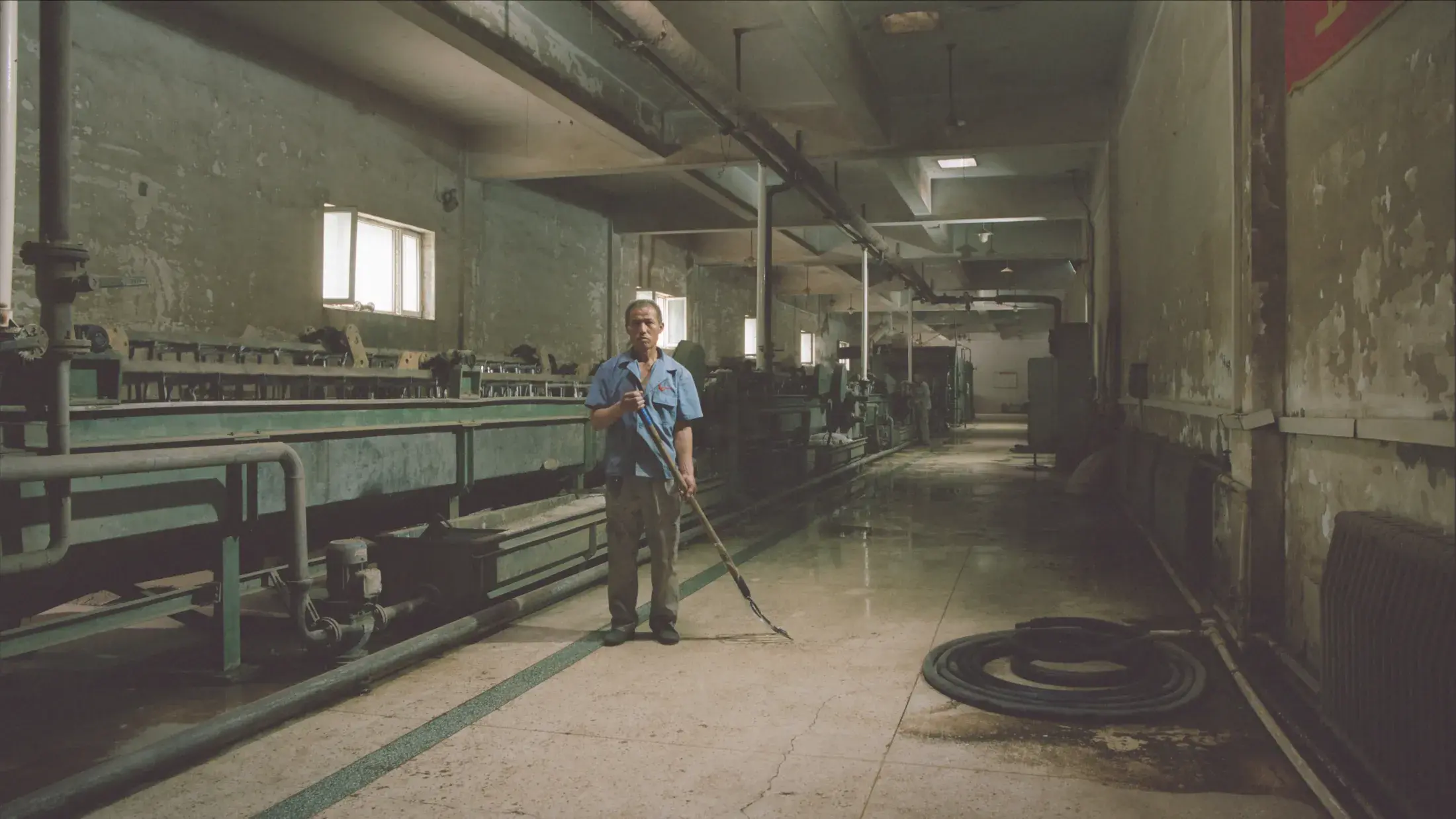 man holding rake in an empty factory