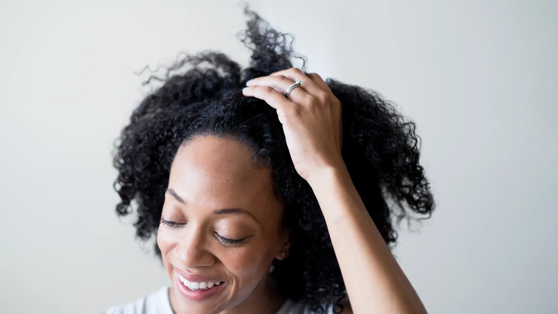 front view of woman smiling while running a hand through her hair