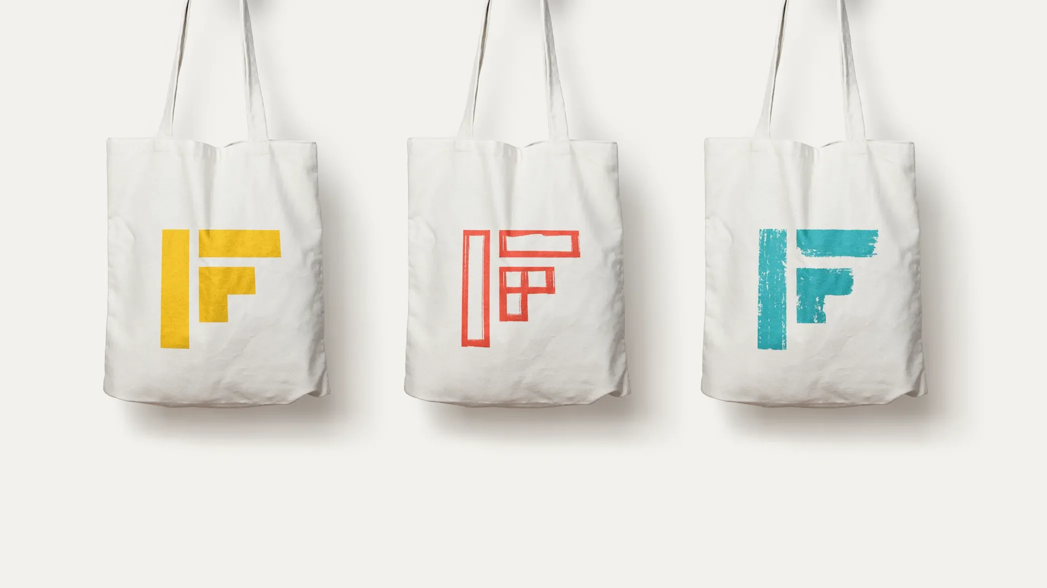 three canvas totes with the idea foundry logo screenprinted on them in yellow red and blue