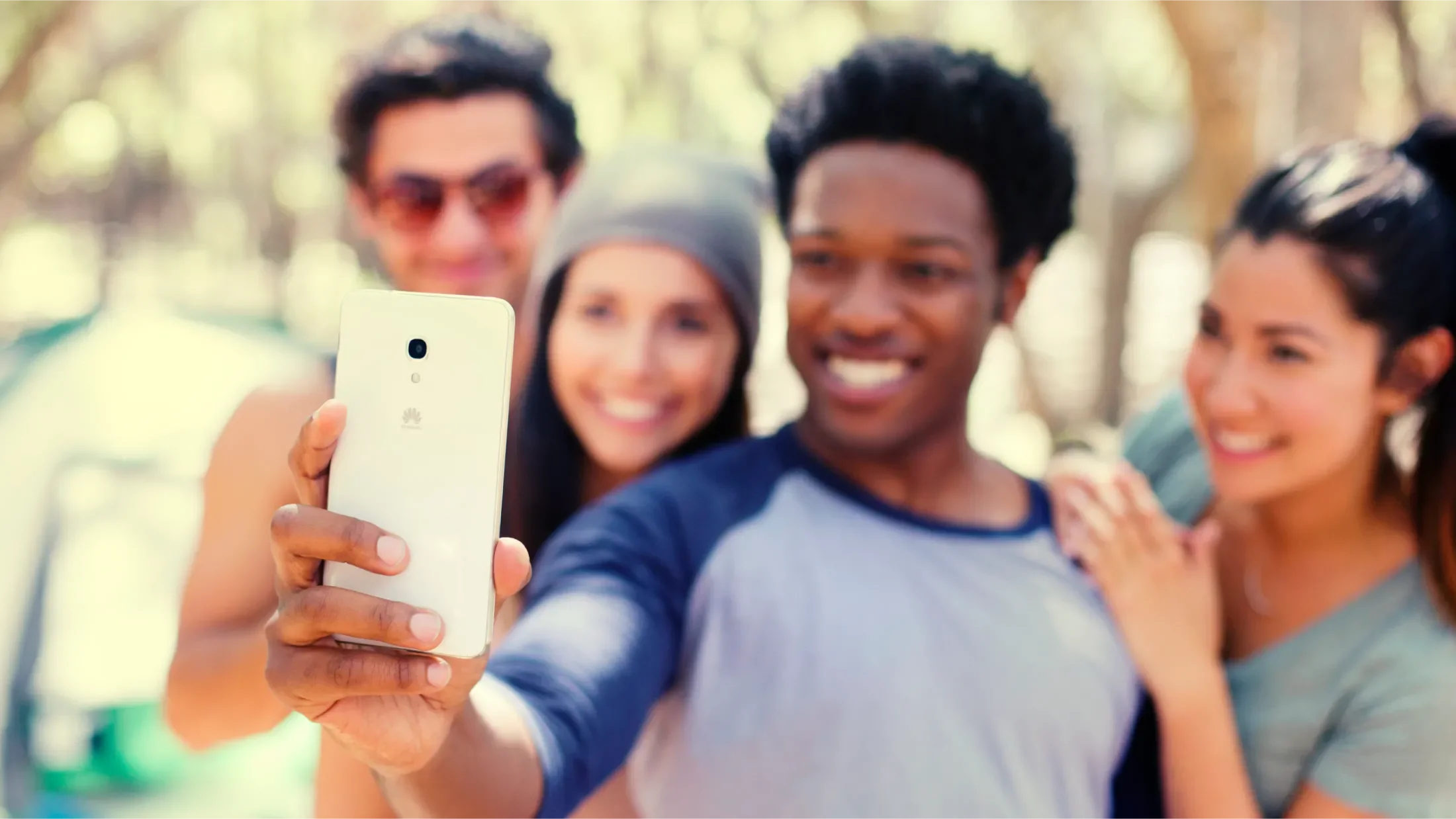 Four young adults taking a selfie with focus placed on the Huawei Ascend Mate2 in their hand as 