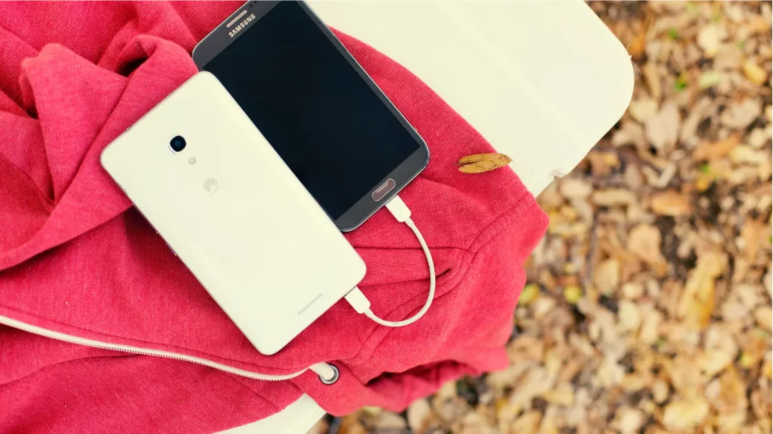 A Huawei Ascend Mate2 connected to a Samsung phone sitting atop a red hoodie