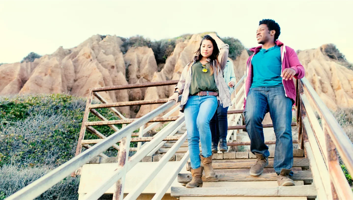 Three young adults walking down a wood staircase in a mountainous setting