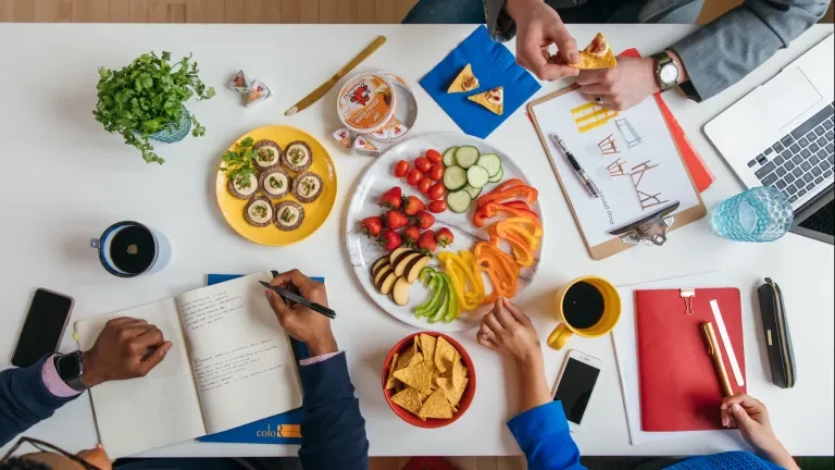 A group of three people doing work while enjoying snacks with Laughing Cow cheese