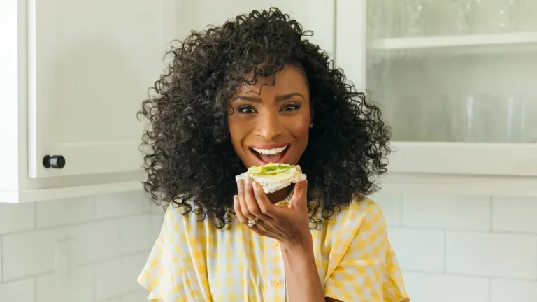 Smiling woman about to eat a cracker with Laughing Cow cheese