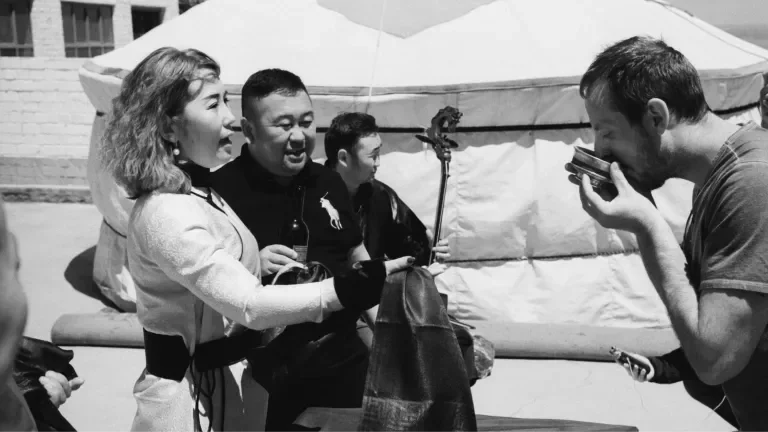 man drinking a ceremonial beverage as his hosts look on