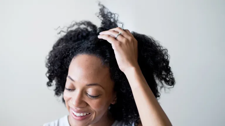 front view of woman smiling while running a hand through her hair