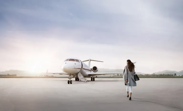 Well-dressed woman walking toward plane during sunrise