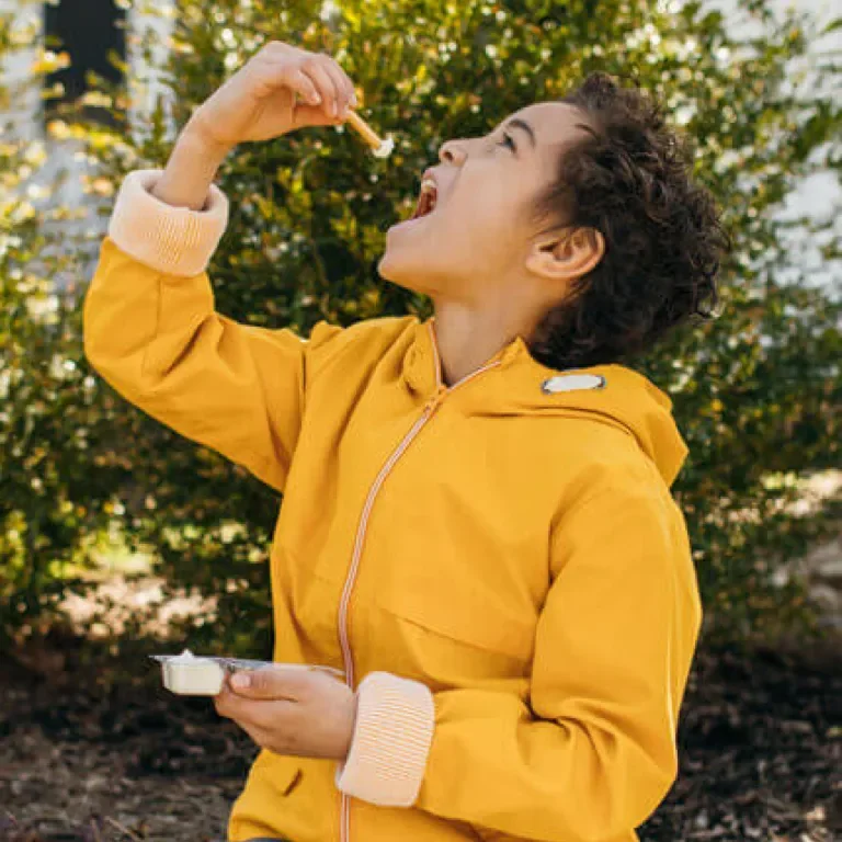 child holding a Cheese Dipper above their face as they go to take a bite