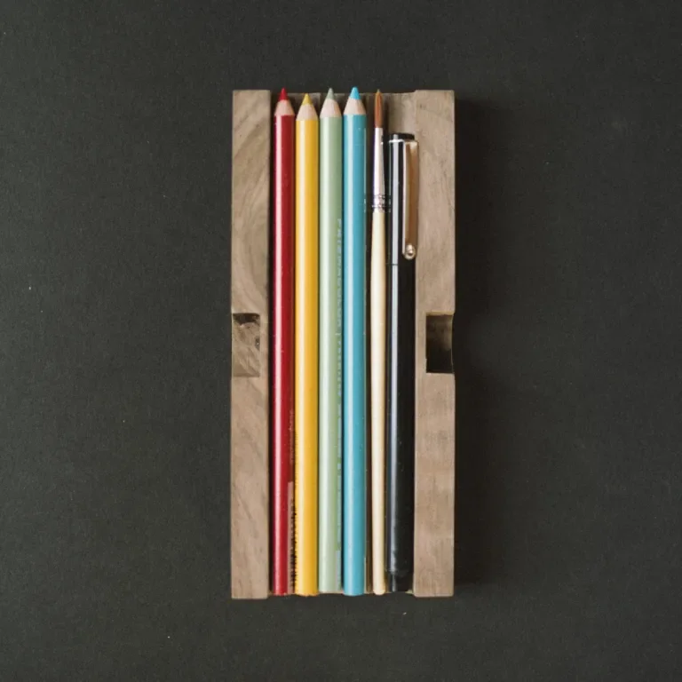 Wooden tray containing colored pencils, a brush and a pen