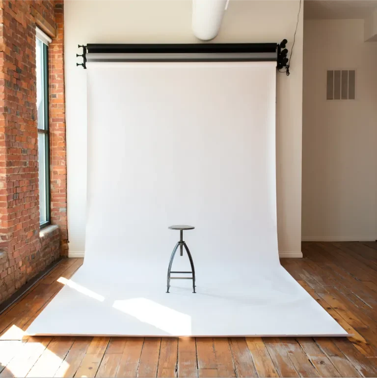 Stool against a draping white backdrop mounted in a spool on the back wall