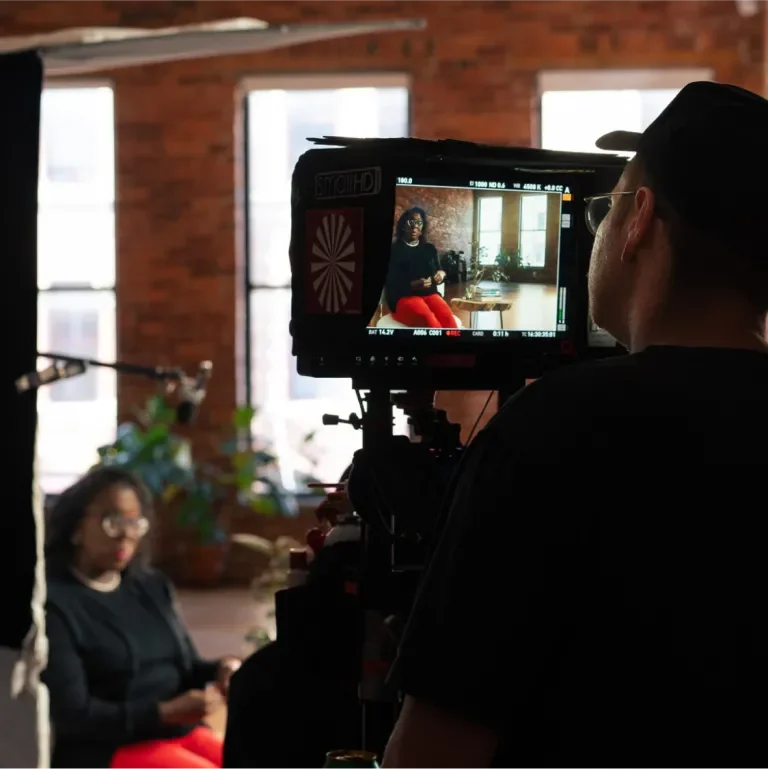 Behind the scenes showing a crew member looking through a monitor while Dr. Jada Jackson is being interviewed