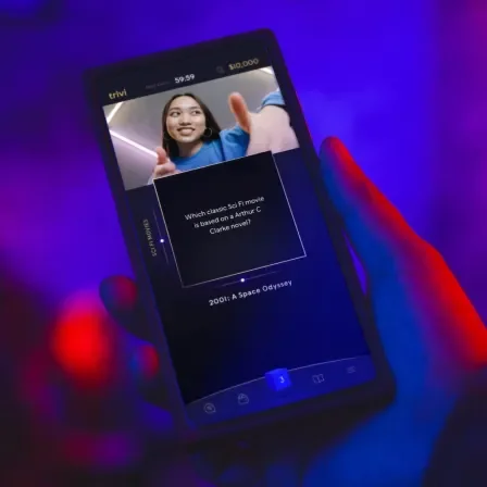 Hand holding a phone with the Trivi app loaded on it