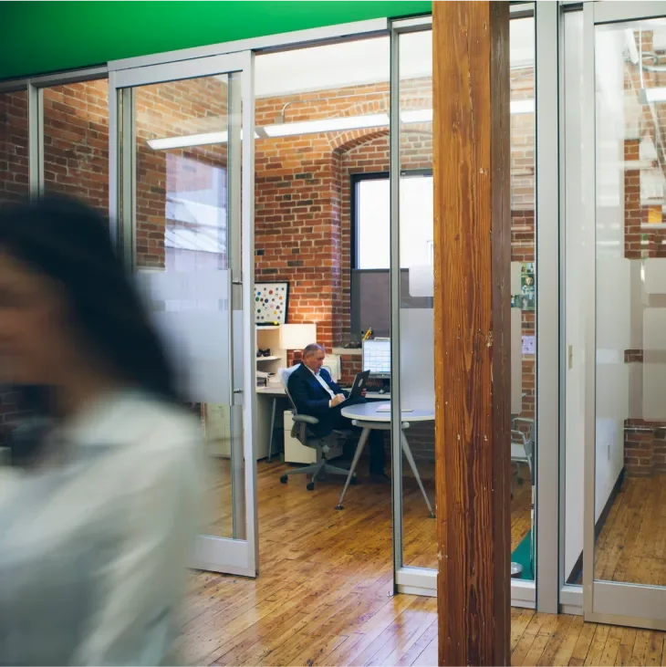 Baesman's office shot of a private office space with a blurred image of someone walking by 
