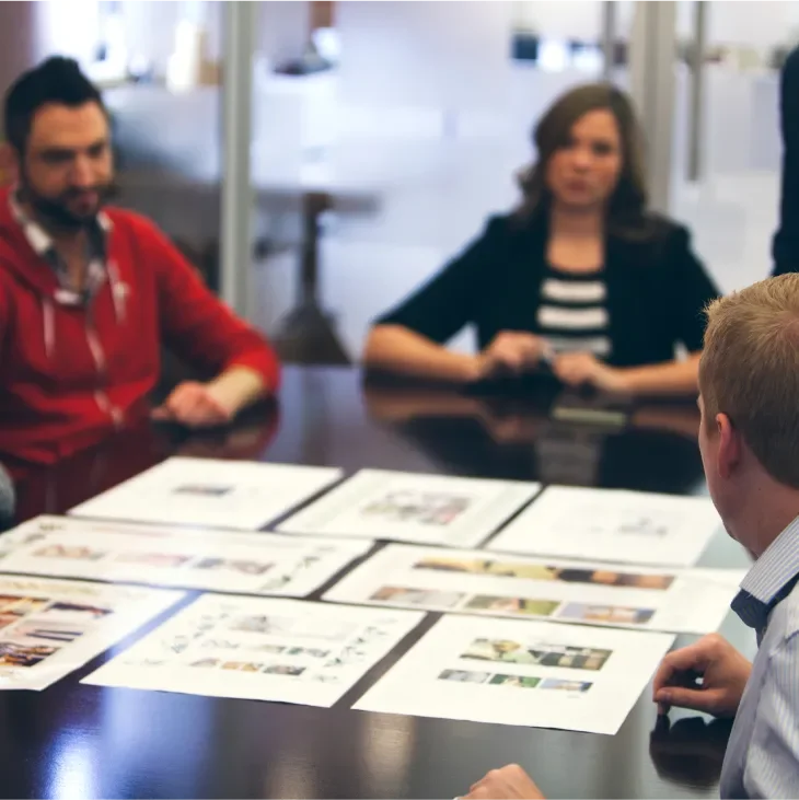 Image of Baesman colleague sitting around a conference table with papers 