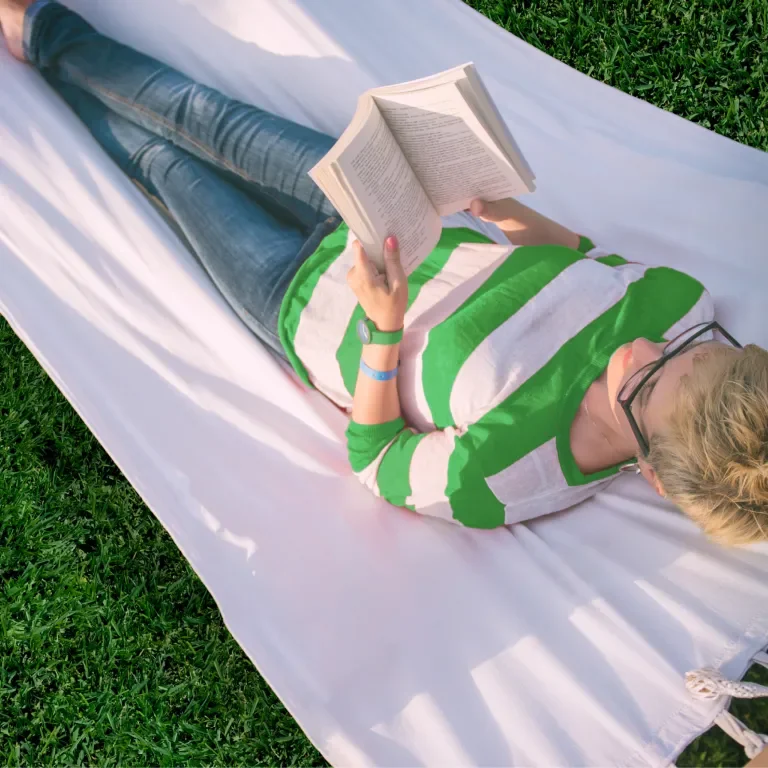 Lifestyle image of someone enjoying their lawn on a hammock reading a book