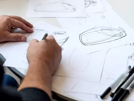 Two people at a table sketching on paper