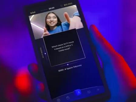 Hand holding a phone with the Trivi app loaded on it
