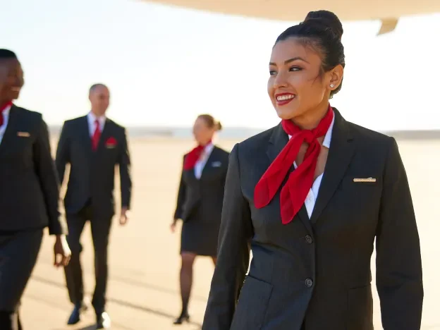 Gridiron Air flight attendants walk under the belly of a Boeing 777 on a tarmac at sunset.