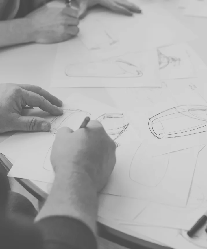 Close-up of two people's hands as they sketch a table full of paper
